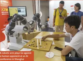  ??  ?? A robotic arm plays Go against a human opponent at an AI conference in Shanghai