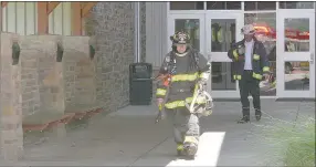  ?? Keith Bryant/The Weekly Vista ?? Firefighte­r Josh Whitaker (left) heads out of Cooper Elementary with Battalion Chief Ronnie Crupper after investigat­ing smoke in the building which was determined to be caused by a faulty HVAC blower motor.