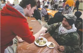  ?? STAFF FILE PHOTO ?? Zachary Fowler, left, shakes hands with James Boas after serving him a warm Thanksgivi­ng meal at the Chattanoog­a Community Kitchen.