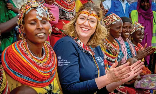  ??  ?? Vibrant: Penny Mordaunt wears an intricate beaded headband and necklace as she meets mothers on her trip to Kenya