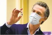  ?? JAE HONG AP FILE ?? Gov. Gavin Newsom holds up a vial of the Pfizer COVID-19 vaccine at a medical center in Los Angeles.