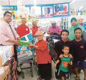  ?? [FOTO MARY VICTORIA DASS /BH] ?? Mohd Zailani bersama ahli keluarga menerima sumbangan disampaika­n Mas Imran di Pasaraya Econsave Cash And Carry Senai, Johor Bahru, semalam.