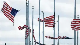  ?? (Joshua Roberts/Reuters) ?? AMERICAN FLAGS are partially torn from their poles on Friday as a strong winter storm passes through Washington on its way northeast toward New England.