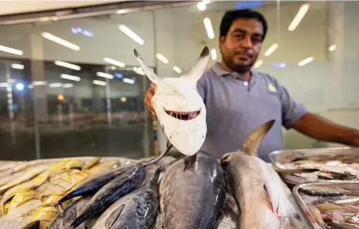  ?? GETTY ANDREW AITCHISON / ?? Un pescadero muestra un tiburón en el Jumeriah Fish Market del puerto de Dubai.