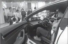 ?? LONG WEI / FOR CHINA DAILY ?? Left: Visitors check out an electric sedan in Hangzhou, Zhejiang province, in December.