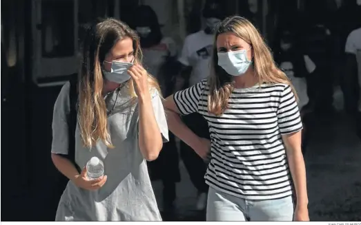  ?? JUAN CARLOS MUÑOZ ?? Dos mujeres caminan con la mascarilla en una calle de Sevilla.