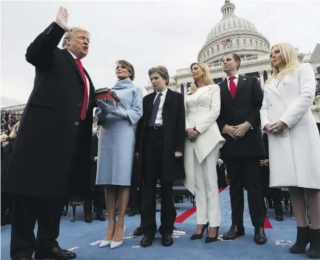  ?? JIM BOURG / POOL PHOTO VIA AP ?? President Donald Trump, surrounded by his family, takes the oath of office from Chief Justice John Roberts.