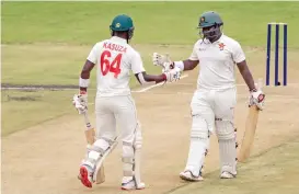  ?? (AFP) ?? Zimbabwe's Prince Masvaure (right) celebrates after scoring a half-century with his teammate Kevin Kasuza during the first day of the first Test against Sri Lanka in Harare on Sunday