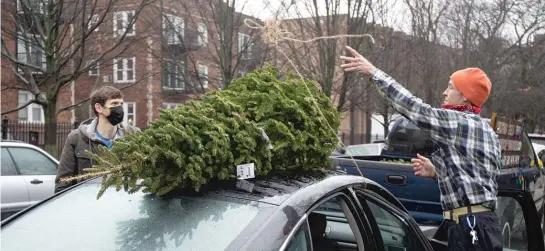  ?? PAT NABONG/ SUN- TIMES ?? Rob Svendsen ( right) helps Shannon Carey secure his tree to the roof of his car on Saturday at Svendsen’s Christmas Trees in Lincoln Park.