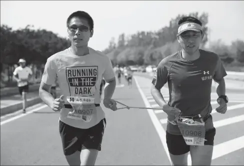  ?? PHOTOS PROVIDED TO CHINA DAILY ?? Yan Wei (left) runs with a volunteer guide in a marathon in Tai’an, Shandong province, in April.