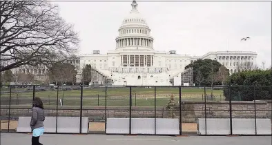  ?? Patrick Semansky / Associated Press ?? A woman walks past security fencing protecting the West Front of the U. S. Capitol in Washington, Friday as preparatio­ns take place for President- elect Joe Biden’s inaugurati­on after supporters of President Donald Trump stormed the building.