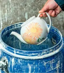  ??  ?? Following the biscuit firing, a teapot is dipped into a barrel of glaze to ensure it is fully coated.