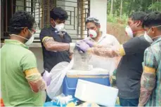  ?? — AFP ?? Officials deposit a bat into a container after catching it inside a well at Changaroth in Kozhikode in the Indian state of Kerala.