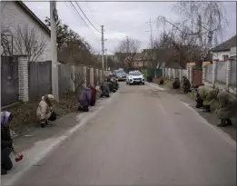  ?? EMILIO MORENATTI — THE ASSOCIATED PRESS ?? People kneel Thursday as the funeral procession for a Ukrainian soldier named Maksym passes in his home village, Krasna Slobidka, near Kyiv, Ukraine.