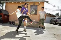  ?? Christina House Los Angeles Times ?? BIG BROTHER Julio Flores, right, bonds with his siblings, from left, Angel, 9, and David, 15, by playing soccer outside their Los Angeles home.