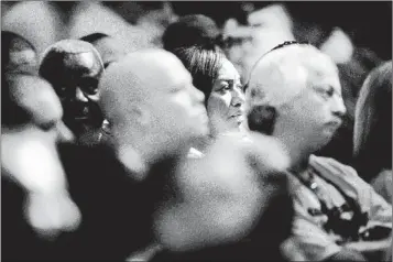  ??                                                                      ?? A beam of light falls on Darlene Smith as she and others listen to budget negotiatio­ns Tuesday evening at City Hall.