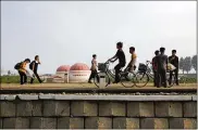  ?? WONG MAYE-E / AP ?? North Koreans walk while some cycle past a factory dome with Korean words painted on its side that read “First priority: self developmen­t” at the end of a work day Thursday in Hamhung. The U.S. plans to bar most Americans from visiting the country.