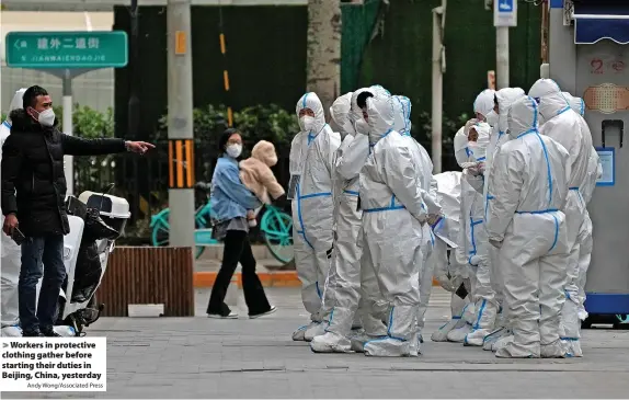  ?? Andy Wong/Associated Press ?? Workers in protective clothing gather before starting their duties in Beijing, China, yesterday