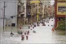  ?? Associated Press photo ?? People move through flooded streets in Havana after the passage of Hurricane Irma, in Cuba, Sunday. The powerful storm ripped roofs off houses, collapsed buildings and flooded hundreds of miles of coastline after cutting a trail of destructio­n across...