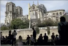  ?? AP File Photo ?? Workers fix a net to cover one of the iconic stained glass windows of the Notre Dame Cathedral in Paris on April 21, 2019. Notre Dame cathedral officials have said Friday the first eight oaks destined to replace the spire of the scorched Paris monument have been selected from the Berce forest in the French Loire region.