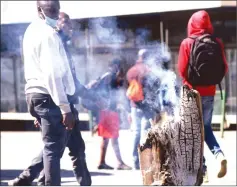  ?? — Picture: John Manzongo ?? Passersby wonder at a burning tree stump in the middle of Harare yesterday at the intersecti­on of Robert Mugabe Road and Cameroon street.