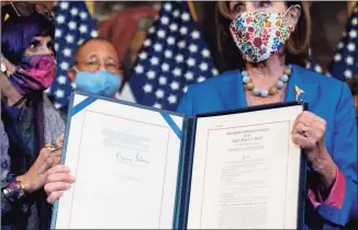  ?? Andrew Harnik / Associated Press ?? House Speaker Nancy Pelosi of California, accompanie­d by Rep. Rosa DeLauro, D-Conn., left, and other House Democrats, holds up a House continuing resolution to keep funding the government after she signed it on Capitol Hill on Thursday.