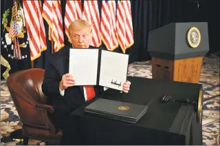  ?? Jim Watson / AFP via Getty Images ?? President Donald Trump signs executive orders extending coronaviru­s economic relief during a news conference in Bedminster, N.J., on Saturday