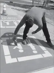  ??  ?? SERGIO MEDRANO PUTS THE FINISHING touches on one of the squares on the sidewalk that encircles the park.