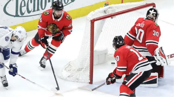  ?? | CHARLES REX ARBOGAST/ AP ?? The Lightning’s Chris Kunitz ( left) banks the puck off Hawks goalie Jeff Glass and into the net for a short- handed goal in the second period Monday.