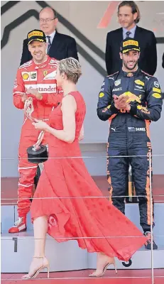  ?? FOTO: RTR ?? Fürstin Charlene bringt die Trophäe für Sebastian Vettel. Rechts applaudier­t Daniel Riccardo, der Platz drei belegt. Links im Hintergrun­d: Fürst Albert II.