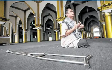  ?? FRAME —MARIANNE BERMUDEZ ?? RAMADAN UNDER MECQ A person with disability prays on Tuesday inside the Golden Mosque in Quiapo, Manila, which opened to limited capacity under the modified enhanced community quarantine, on the first day of Ramadan. After the fast from dawn to dusk, freshly cooked fish—which can be part of the communal meal Muslims traditiona­lly have during the holy month—awaits worshipper­s outside the mosque.