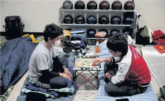  ??  ?? Fans, who were affected by Typhoon Hagibis, play a game at a makeshift accommodat­ion for spectators of the Japanese Grand Prix at Suzuka.
