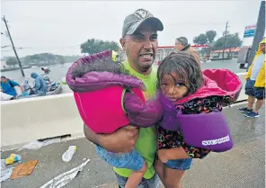  ??  ?? A man carries two children rescued from the floods. Right, residents flee in boats in east Houston