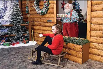  ?? JIM MONE / AP ?? Santa (Sid Fletcher) and Kendra Alexander, of St. James, Minn., are separated by a glass barrier in a log cabin as they pose during her visit Nov. 15 at The Santa Experience in the Mall of America in Bloomingto­n, Minn. Where allowed, some malls and big-box stores are offering Santa’s guests a choice of full contact or social distance.