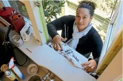  ?? PHOTO: JEFFREY KITT/FAIRFAX NZ ?? Ward resident Candi Callaghan uses newspaper to patch the kitchen window sill of her home, which is yet to be assessed by insurers.