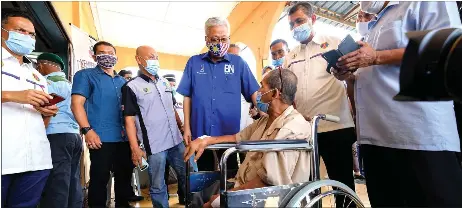  ?? — Bernama photo ?? Ismail Sabri (centre) conducts a visit to the house of an army veteran Juragan Buyong, 60, after attending an event with members of the Slim River branch of the PVATM at Felda Besout 2.