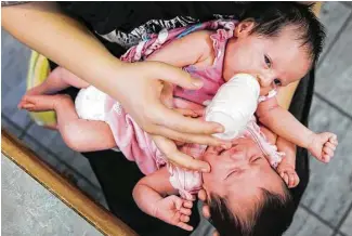  ?? Elizabeth Conley / Houston Chronicle ?? Callie Torres takes a bottle next to her conjoined sister, Carter, on Friday in Houston. The girls were delivered by cesarean section last month at Texas Children’s Hospital.