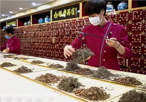  ??  ?? Injecting new methods: An employee weighing ingredient­s at a traditiona­l medicine pharmacy in Beijing. The Chinese medicine sector has modernised along with the rest of the country, with some local manufactur­ers turning age-old recipes into fastacting...