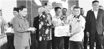  ??  ?? Patrick (second right) presenting a souvenir to Tangau at the launching of FIKS and OD1SI in Tamparuli on Wednesday.