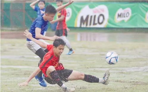  ?? SUNSTAR FOTO/ AMPER CAMPAÑA ?? WATERWORLD. Footballer­s from Paref Springdale and Bayawan National High School slip in the muddy football field during the Milo Little Olympics.