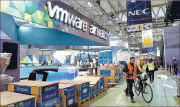  ?? LLUIS GENE / AFP ?? People walk past a stand of VMware at an industry expo in Barcelona, Spain. The company is undergoing a business transition to grow its cloud products and services, especially in countries like China.