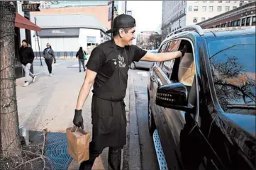  ?? TERRENCE ANTONIO JAMES/CHICAGO TRIBUNE ?? Jesus Garcia of Virtue in Hyde Park hands off an order to a curbside customer Wednesday.