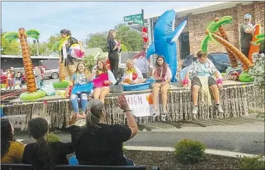  ?? Westside Eagle Observer/SUSAN HOLLAND ,Westside Eagle Observer/ SUSAN HOLLAND ?? The freshman class float in the Gravette High School homecoming parade featured a beach theme with some class members dressed in grass skirts and leis. Palm trees, beach balls and surfboards decorated the float with a friendly dolphin waving to the crowd.