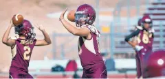  ??  ?? Quarterbac­ks for Santa Fe Indian School, Alec Lee, left, and Dominic Star pass the ball during practice.