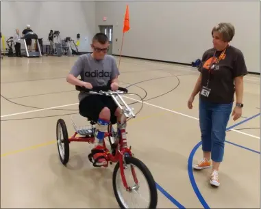  ?? ZACHARY SRNIS — THE MORNING JOURNAL ?? Cole Quintana, 14, a seventh-grader at North Ridgeville Academic Center, rides the new Amtryke bike Sept. 6 after being strapped in by Jennifer Phelan, a paraprofes­sional at the school.