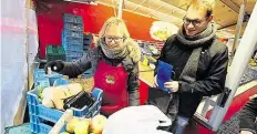  ??  ?? Übergabe: Eine Mitarbeite­rin vom Fruchthand­el Hüttemeyer (links) überreicht das aussortier­te Obst und Gemüse.
