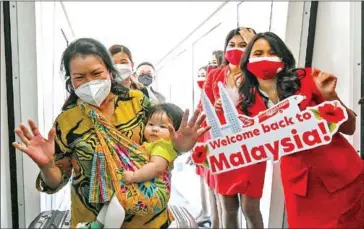  ?? AFP ?? A woman carries an infant after landing at Kuala Lumpur Internatio­nal Airport 2, as Malaysia reopened its borders for travellers fully vaccinated against the Covid-19 coronaviru­s, in Sepang on April 1.