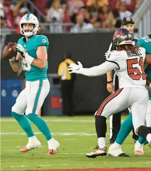  ?? JASON BEHNKEN/AP ?? Dolphins quarterbac­k Skylar Thompson looks for a receiver against the Buccaneers during the first half of Saturday’s preseason game in Tampa.