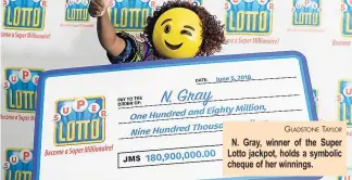  ?? GLADSTONE TAYLOR ?? N. Gray, winner of the Super Lotto jackpot, holds a symbolic cheque of her winnings.