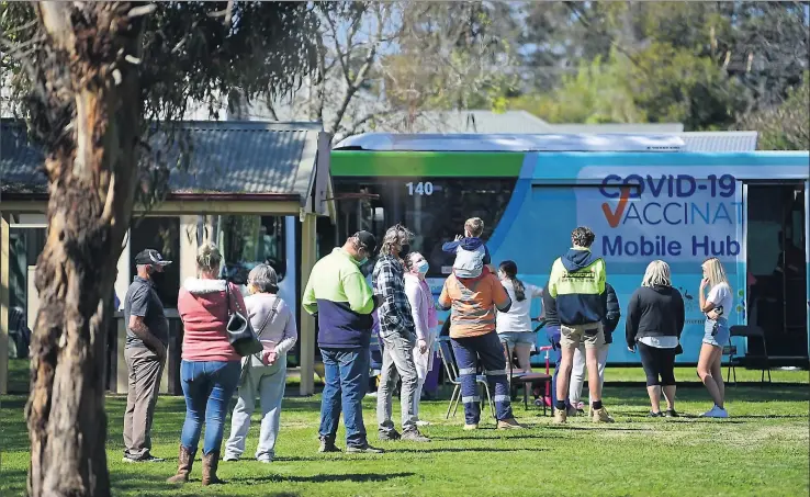  ?? Pictures: Rodney Braithwait­e ?? Welcome visitor: Merrigum residents keen to get vaccinated line up outside Jabba the Bus yesterday.
